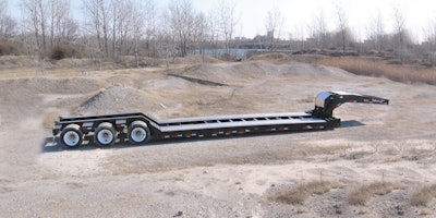 An unloaded gooseneck trailer on a work site.