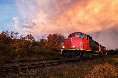 Red train engine sitting on the tracks at sunset.