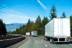 Three tractor-trailers going down the road into the mountains.
