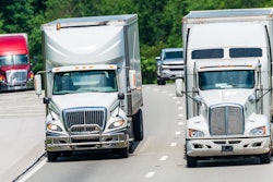 Trucks driving over hill and down highway