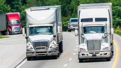 Trucks driving over hill and down highway