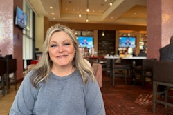 A smiling woman sitting at a table in a restaurant.