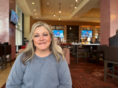 A smiling woman sitting at a table in a restaurant.