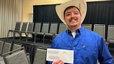 Man with a cowboy hat holding a check.