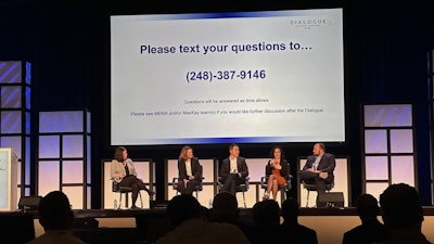 A group of people seated onstage at a conference.