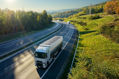 A truck going down a mountain highway on a sunny day.