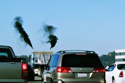 A truck in traffic with exhaust.