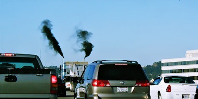 A truck in traffic with exhaust.