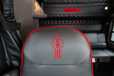 A gray leater seat with red accents and stitching