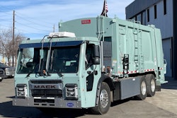 A mint green Mack LR Electric refuse truck at Bruckner Truck Sales in Commerce City, Colorado.