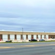 The exterior of a new truck center showing repair bays and an entrance under a cloudy sky.