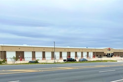The exterior of a new truck center showing repair bays and an entrance under a cloudy sky.