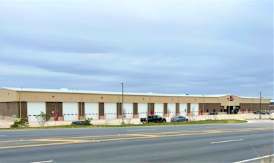 The exterior of a new truck center showing repair bays and an entrance under a cloudy sky.