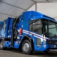 A blue garbage truck in a white building.