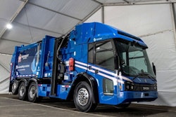 A blue garbage truck in a white building.