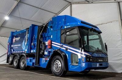 A blue garbage truck in a white building.