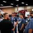 A group of men talking in front of several Class 8 trucks