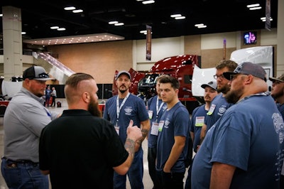 A group of men talking in front of several Class 8 trucks