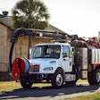 A white sewer cleaning truck in front of a house and palm tree.