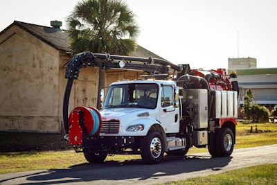 A white sewer cleaning truck in front of a house and palm tree.