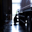 A silhouette of a man working on a truck.