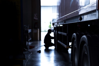 A silhouette of a man working on a truck.