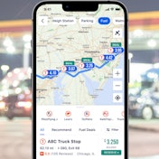 A screenshot of the Trucker Path app with a fuel station in the background.