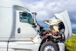 White semi-truck parked on highway with hood raised