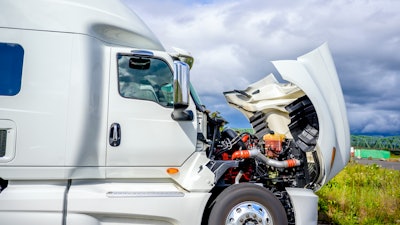 White semi-truck parked on highway with hood raised