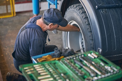 Technician working on wheel end and tire