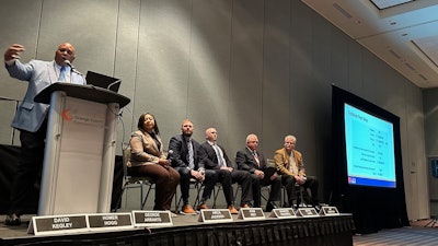 A group of people on a stage talking through a problem.