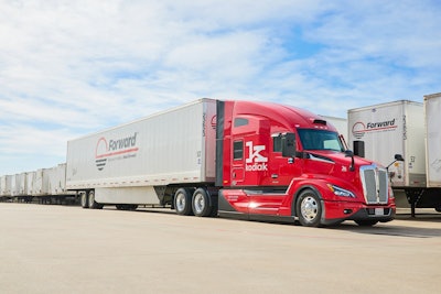 A red Kodiak autonomous truck pulling a white Forward trailer in a lot.