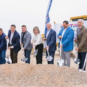 A group of people shoveling dirt on a building site.