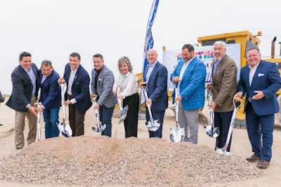 A group of people shoveling dirt on a building site.