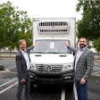 Two men flanking an EV refrigerated box truck.