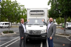 Two men flanking an EV refrigerated box truck.