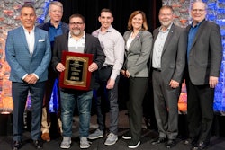 People standing on stage with a plaque.