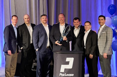 A row of men holding an award on a stage in front of a PacLease podium.
