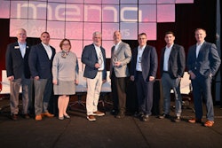 A group of people on stage in front of a MEMA sign.