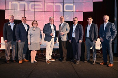 A group of people on stage in front of a MEMA sign.