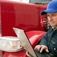 Man holding laptop while standing by truck