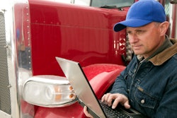 Man holding laptop while standing by truck