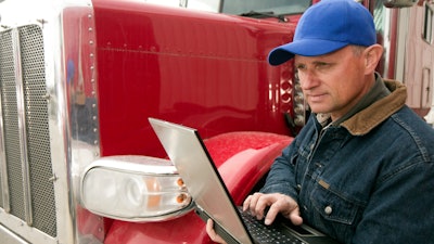 Man holding laptop while standing by truck
