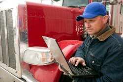 Man standing next to a truck holding a laptop