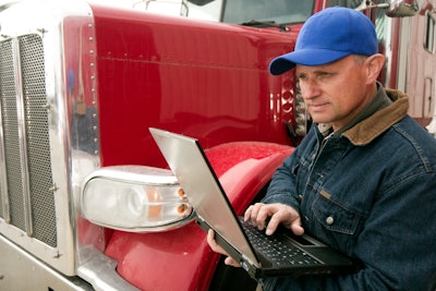 Man standing next to a truck holding a laptop