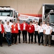 A group of young men in front of two trucks.
