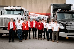 A group of young men in front of two trucks.