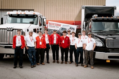 A group of young men in front of two trucks.