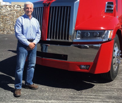 A man standing in front of a red Class 8 truck.