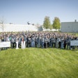 A group of happy people standing outside of a large BorgWarner manufacturing plant.